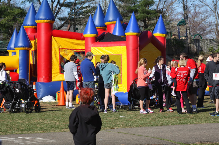 A colorful inflatable castle on the school grounds with families gathered nearby